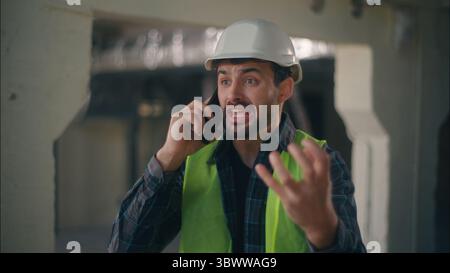 Wütender kaukasischer Vorarbeiter spricht Handy im Bauingenieur männlich schreiend wütender Inspektor Mann streitet Handy-Anruf Stockfoto
