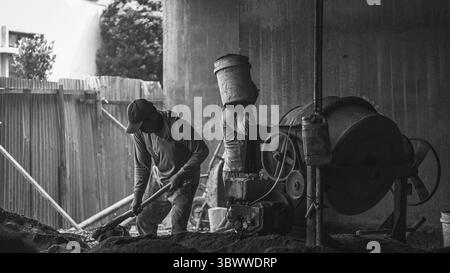 Bauarbeiter mischen Baumaterialien wie Zement, Sand und Wasser, um eine starke Mischung zu schaffen, die für eine dauerhafte und effektive Konstruktion unerlässlich ist Stockfoto