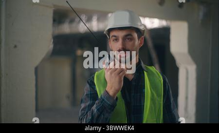 Professioneller kaukasischer Baumeister spricht Walkie-Talkie im Bauelektriker-Vorarbeiter, der technischen Input-Ingenieur-Inspektor hält, der kommuniziert Stockfoto