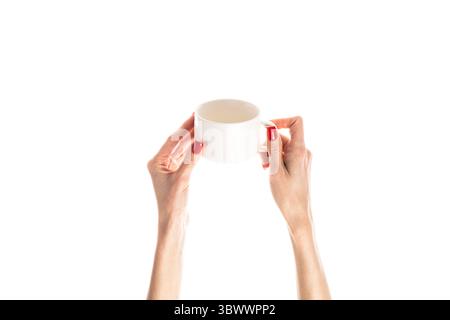 Weibliche Hände halten einen weißen Keramikbecher auf weißem Hintergrund. Weibliche Hände mit frischer roter Maniküre. Isoliert auf weißem Hintergrund. Stockfoto