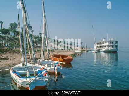 7. März 1981, Ägypten: Feluccas, traditionelle Holzsegelboote, die auf dem Nil eingesetzt werden, liegen im Vordergrund. Im Hintergrund befindet sich eine große Fähre, die Touristen über den Fluss vom Tal der Könige in die moderne Stadt Luxor und die antiken Ruinen des Tempels von Karnak bringt. (Bild: © Arnold Drapkin/ZUMA Press Wire) Stockfoto