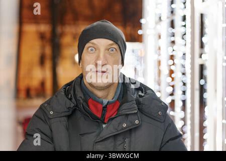 Mann auf der Straße im Winter, helle Lichter, Gesichtsausdrücke Stockfoto