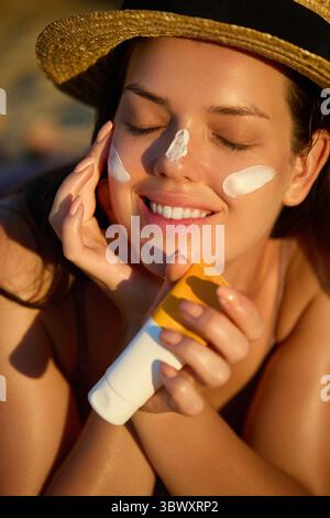 Frau mit schönem Gesicht, das gesundes Gesichtshaut-Porträt berührt. Beauty Close Up Girl trägt ein Hautpflegeprodukt Sonnencreme oder feuchtigkeitsspendende Sonne auf Stockfoto