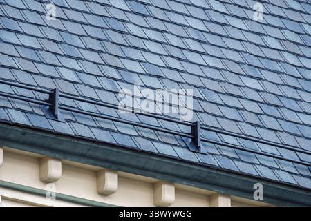 Detaillierte Ansicht eines schrägen Asphaltschindeldachs mit installierter Schneeschutzschiene, die Schneerutschen verhindert und Eigentum bei kaltem Klima schützt Stockfoto