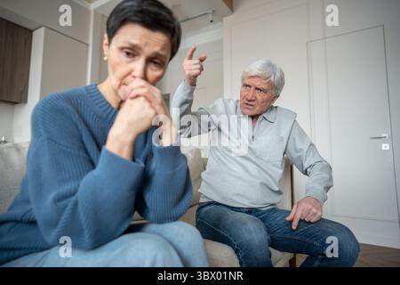 Wütender Seniorenmann mit missbräuchlichem Schreien zu trauriger Frau, Familienzusammenbruch in emotionaler Kontrolle Stockfoto