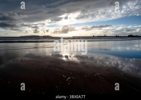 Sonnenuntergang an den riesigen Stränden von Essaouira mit blauem Himmel, weißen Wolken und Wellen, die am Ufer in Marokko zusammenbrechen Stockfoto