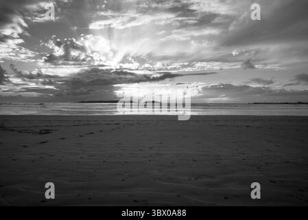 Sonnenuntergang an den riesigen Stränden von Essaouira mit blauem Himmel, weißen Wolken und Wellen, die am Ufer in Marokko zusammenbrechen Stockfoto