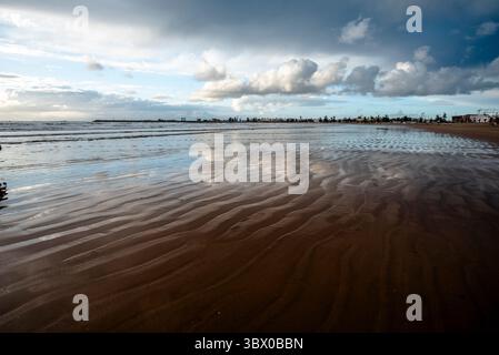 Sonnenuntergang an den riesigen Stränden von Essaouira mit blauem Himmel, weißen Wolken und Wellen, die am Ufer in Marokko zusammenbrechen Stockfoto