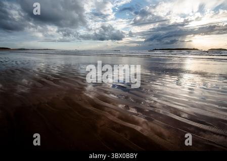 Sonnenuntergang an den riesigen Stränden von Essaouira mit blauem Himmel, weißen Wolken und Wellen, die am Ufer in Marokko zusammenbrechen Stockfoto