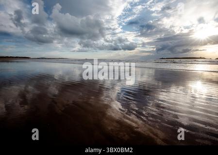 Sonnenuntergang an den riesigen Stränden von Essaouira mit blauem Himmel, weißen Wolken und Wellen, die am Ufer in Marokko zusammenbrechen Stockfoto