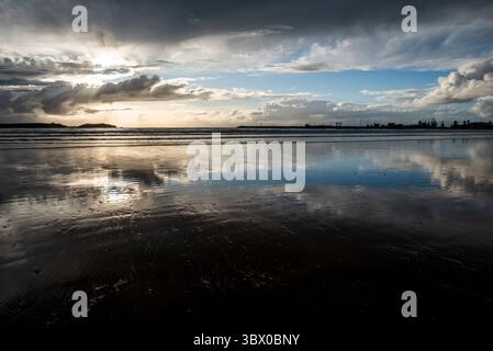 Sonnenuntergang an den riesigen Stränden von Essaouira mit blauem Himmel, weißen Wolken und Wellen, die am Ufer in Marokko zusammenbrechen Stockfoto