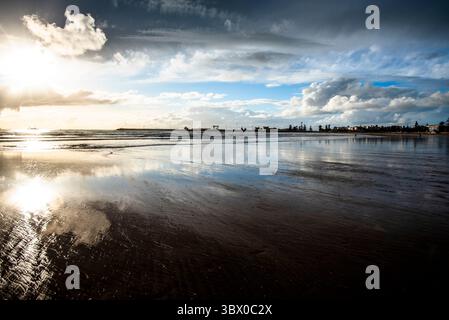 Sonnenuntergang an den riesigen Stränden von Essaouira mit blauem Himmel, weißen Wolken und Wellen, die am Ufer in Marokko zusammenbrechen Stockfoto