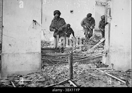 OOSTERBEEK, NIEDERLANDE – 23. September 1944 – vier Fallschirmjäger der britischen Armee (wahrscheinlich von der 4. Fallschirmbrigade), die sich durch einen Panzerdama bewegen Stockfoto