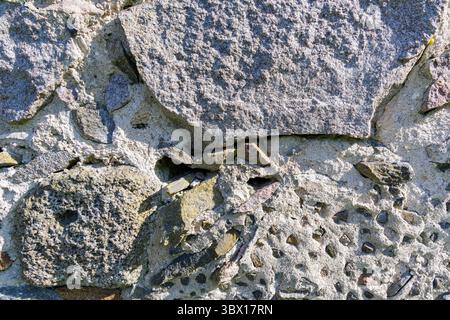 Nahaufnahme einer zerklüfteten Steinmauer mit verwitterten Felsen und Mörtel, ideal für Hintergründe und historische Themen. Stockfoto