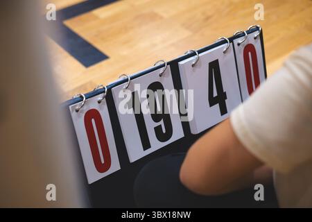 Nahaufnahme einer manuellen Anzeigetafel auf dem Boden des Fitnessstudios, deren Karten 0 19 4 0 zeigen, während sich ein Spiel entfaltet, und die taktile Intensität von Live-Sportarten erfassen Stockfoto