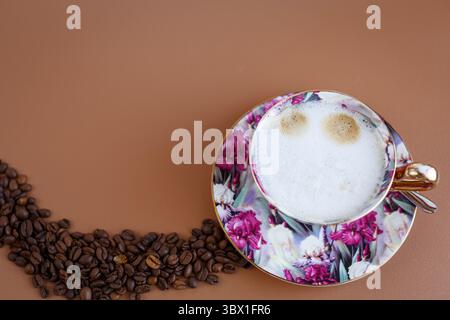 Gemütlicher Cappuccino auf warmbrauner Oberfläche mit Bohnen. Stockfoto