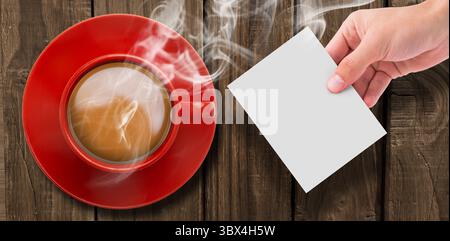 Blick von oben auf heißen Tee, indem man die Seite von Hand über dem Holztisch hält Stockfoto