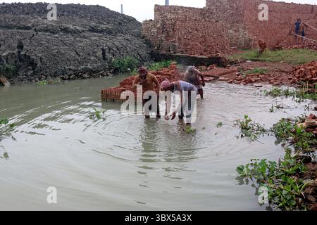 4. September 2021, Dhaka, Bangladesch: Ein Migrant aus Bangladesch hält Ziegelblöcke über seinem Kopf, um es auf der anderen Seite des Flusses an einem Ziegelfeld in Keraniganj zu transportieren. Rund 400.000 einkommensschwache Migranten kommen jedes Jahr nach Dhaka, um in brickfields zu arbeiten, in der Ziegelfabrik werden Millionen von Ziegeln verbrannt, obwohl dies die Umwelt in Bangladesch beeinträchtigt. Ein Arbeiter zieht einen Wagen mit Ziegeln, der auf dem Keraniganj Ziegelfeld verbrannt werden kann. Steinarbeiter arbeiten 7 Tage die Woche und erhalten 350 BDT (4,37 USD) pro Tag. (Bild: © Habibur Rahman/ZUMA Press Wire Service) Stockfoto