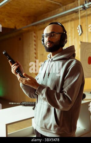 Porträt einer Person, die Sicherheitsausrüstung trägt, während der Feuerwaffenübung am Schießstand, Sicherheitsmaßnahmen erlernen. Mann aus dem Nahen Osten, der die Waffe lädt, die Selbstverteidigung vorbereitet Stockfoto