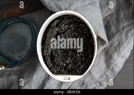Gemahlene schwarze Sesamsamen in einer elektrischen Gewürzmühle: Gepulverte schwarze Sesamsamen in einer Kaffeemühle, von oben gesehen Stockfoto