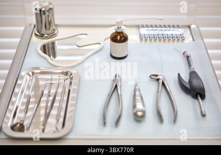 Nahaufnahme von Dentalinstrumenten aus Edelstahl, die auf einem sterilen Tablett angeordnet sind. Zu den Werkzeugen gehören Sonden, Pinzetten und Aufzüge, die üblicherweise für o verwendet werden Stockfoto