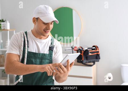 Männlicher Klempner mit Tablet-Computer im Badezimmer Stockfoto
