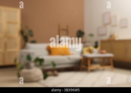 Sofa, Hocker und Zimmerpflanzen im Inneren des Wohnzimmers, verschwommener Blick Stockfoto