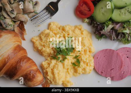 Frühstücksteller mit Rührei und Croissant Stockfoto