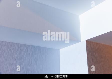 Geometrische Architekturformen schaffen ein abstraktes Muster an einer strukturierten Decke mit sanfter Beleuchtung. Das ima verfügt über ein minimalistisches und modernes Design Stockfoto