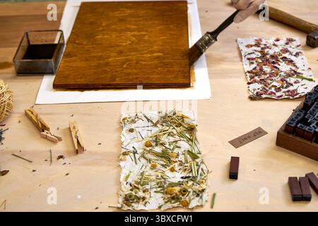 Bürsten der Holzplatte für dekoratives Kunsthandwerk mit handgefertigtem Blumenpapier. Umweltfreundliches Kunstprojekt mit natürlichen Materialien und botanischem Papier. Kreative DI Stockfoto