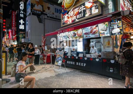 Eine geschäftige Abendszene im berühmten Viertel Dotonbori in Osaka, Japan. Menschenmassen laufen durch die lebhaften Restaurants und Geschäfte. Stockfoto