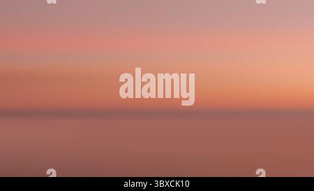 Ein ruhiger Sonnenuntergang mit warmen rosa bis orangen Farbtönen, die sich über einem ruhigen Ozean spiegeln. Im Freien, um einen friedlichen Horizont zu erwecken, ideal für Naturszenen o Stock Vektor