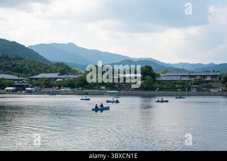 Die Menschen genießen es, kleine Boote auf einem ruhigen Fluss in Arashiyama, Kyoto, Japan zu rudern. Kyoto, Japan. 07.18.2025. Stockfoto