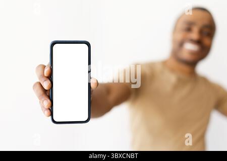 Nahaufnahme eines schwarzen Mannes, der ein Smartphone mit leerem Bildschirm hält Stockfoto