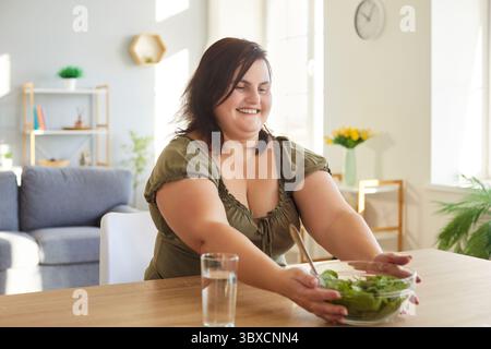Fröhlich von glücklicher positiver Plus Größe Frau versucht, gesunde Essgewohnheiten zu haben, sich an Diät zu halten Stockfoto