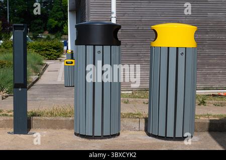 Zwei graue Mülleimer mit schwarzen und gelben Deckeln symbolisieren städtische Abfalltrennung und praktische Umweltgestaltung. Stockfoto