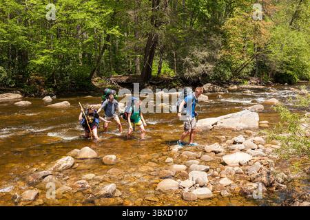 Studentinnen und Studenten navigieren sicher über eine Flussüberquerung im Cranber Stockfoto