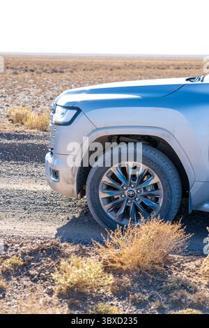 Altai, Kasachstan - 12. Oktober 2024: Nahaufnahme des Vorderrads und des Kotflügels eines silbernen Toyota Land Cruiser 300, geparkt in einer trockenen Wüstenlandschaft Stockfoto