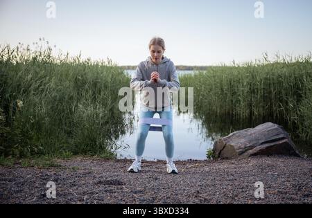 Frau, die im Sommer in der Nähe des Sees Widerstandstruppen macht Stockfoto