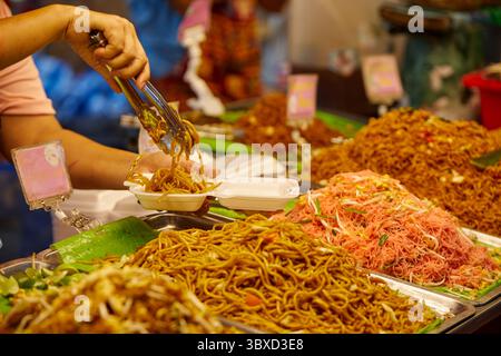 Ein Verkäufer verkauft Yakisoba-Nudeln in einer Plastikbox auf dem Straßenmarkt Stockfoto
