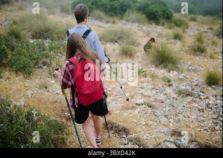 Zwei Wanderer durchqueren einen felsigen Bergpfad, der von üppiger Vegetation umgeben ist. Eine ruhige Umgebung, die Outdoor-Abenteuer, Gesundheit und eine Verbindung fördert Stockfoto