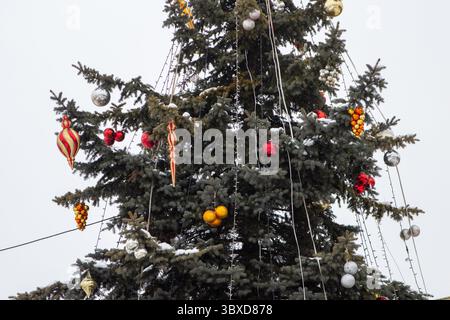 Große antike Kugeln und Eiszapfen hängen draußen am Weihnachtsbaum Stockfoto