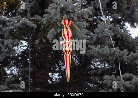 Großes weihnachtsspielzeug auf Tanne, roter Eiszapfen hängt auf Tanne Stockfoto