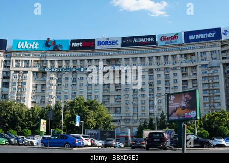 Bukarest, Rumänien – 13. Juli 2025: Wohnblocks, Autos auf dem Parkplatz und Werbetafeln von Marken auf dem Siegesplatz Stockfoto