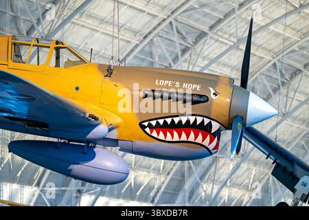 CHANTILLY, Virginia — das Curtiss P-40E Warhawk Kampfflugzeug zeigt die unverwechselbare Haifischschnasen-Kunst, die mit den Flying Tigers im Boeing Aviation Hangar im Steven F. Udvar-Hazy Center assoziiert ist. Dieses einmotorige, einsitzige Jagdflugzeug erwies sich in der ersten Hälfte des Zweiten Weltkriegs als vielseitig und diente in verschiedenen Theatern, darunter in China, wo General Claire Chennault's American Volunteer Group gegen japanische Streitkräfte flog. Curtiss-Wright baute dieses Flugzeug als Modell 87-A3 und lieferte es 1941 als Kittyhawk I nach Kanada, wo es mit der No. 111 Squadron der Roya diente Stockfoto