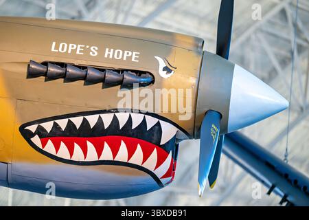 CHANTILLY, Virginia — das Curtiss P-40E Warhawk Kampfflugzeug zeigt die unverwechselbare Haifischschnasen-Kunst, die mit den Flying Tigers im Boeing Aviation Hangar im Steven F. Udvar-Hazy Center assoziiert ist. Dieses einmotorige, einsitzige Jagdflugzeug erwies sich in der ersten Hälfte des Zweiten Weltkriegs als vielseitig und diente in verschiedenen Theatern, darunter in China, wo General Claire Chennault's American Volunteer Group gegen japanische Streitkräfte flog. Curtiss-Wright baute dieses Flugzeug als Modell 87-A3 und lieferte es 1941 als Kittyhawk I nach Kanada, wo es mit der No. 111 Squadron der Roya diente Stockfoto