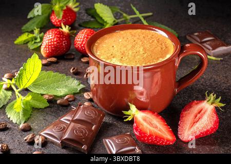 Eine gemütliche Kaffeeszene mit frischen Erdbeeren, reichhaltiger Schokolade und glänzenden Kaffeebohnen auf einer rustikalen Holzoberfläche. Perfekt zum Essen und Mitnehmen Stockfoto