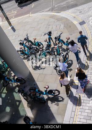 Fußgänger bewegen sich in der City of London, Großbritannien, um zahlreiche Mietfahrräder herum, die auf dem Bürgersteig herumlaufen, was die wachsende Besorgnis über die Behinderung des öffentlichen Raums durch Fahrräder ohne Dock hervorhebt. Stockfoto