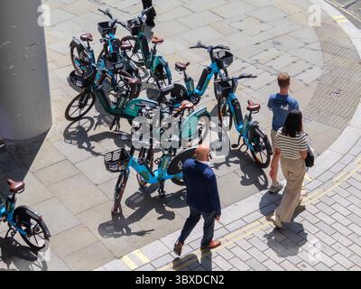 Fußgänger bewegen sich in der City of London, Großbritannien, um zahlreiche Mietfahrräder herum, die auf dem Bürgersteig herumlaufen, was die wachsende Besorgnis über die Behinderung des öffentlichen Raums durch Fahrräder ohne Dock hervorhebt. Stockfoto
