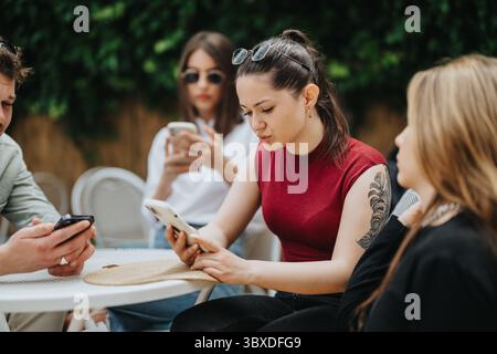 Freunde trafen sich im Freien mit Smartphones in einer geselligen und entspannten Umgebung Stockfoto